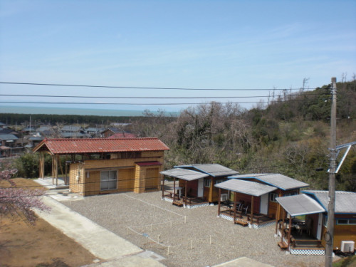 キャンプエリアから見たコテージ全景、建物の向こうは日本海が一望です