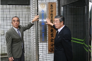 市東粟倉総合支所入口へ看板を掲げる菊池会長、鳥元代表理事