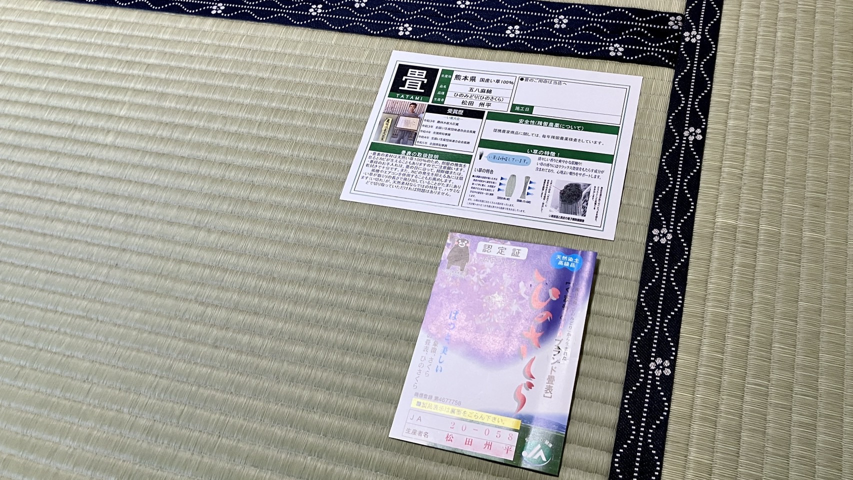 納品された青畳の上に置かれた松田州平氏の顔写真付き品質証明書ひのさくらと五八麻綿の生産者表示証のエビデンス写真｜佐藤畳工業