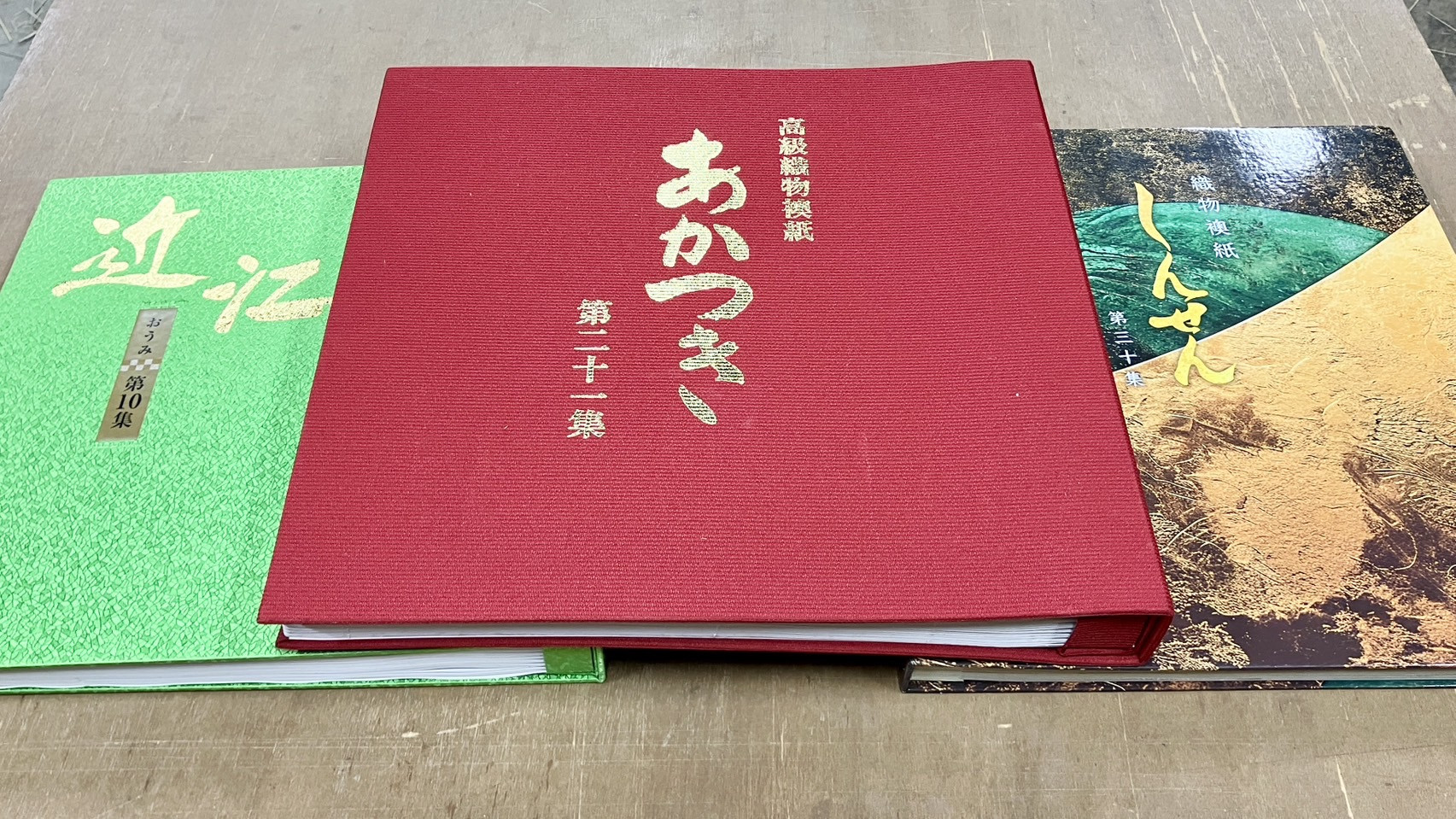 佐藤畳工業が取り扱う高級織物襖紙「あかつき」や「しんせん」「近江」の見本帳カタログが作業台に並ぶエビデンス写真｜佐藤畳工業
