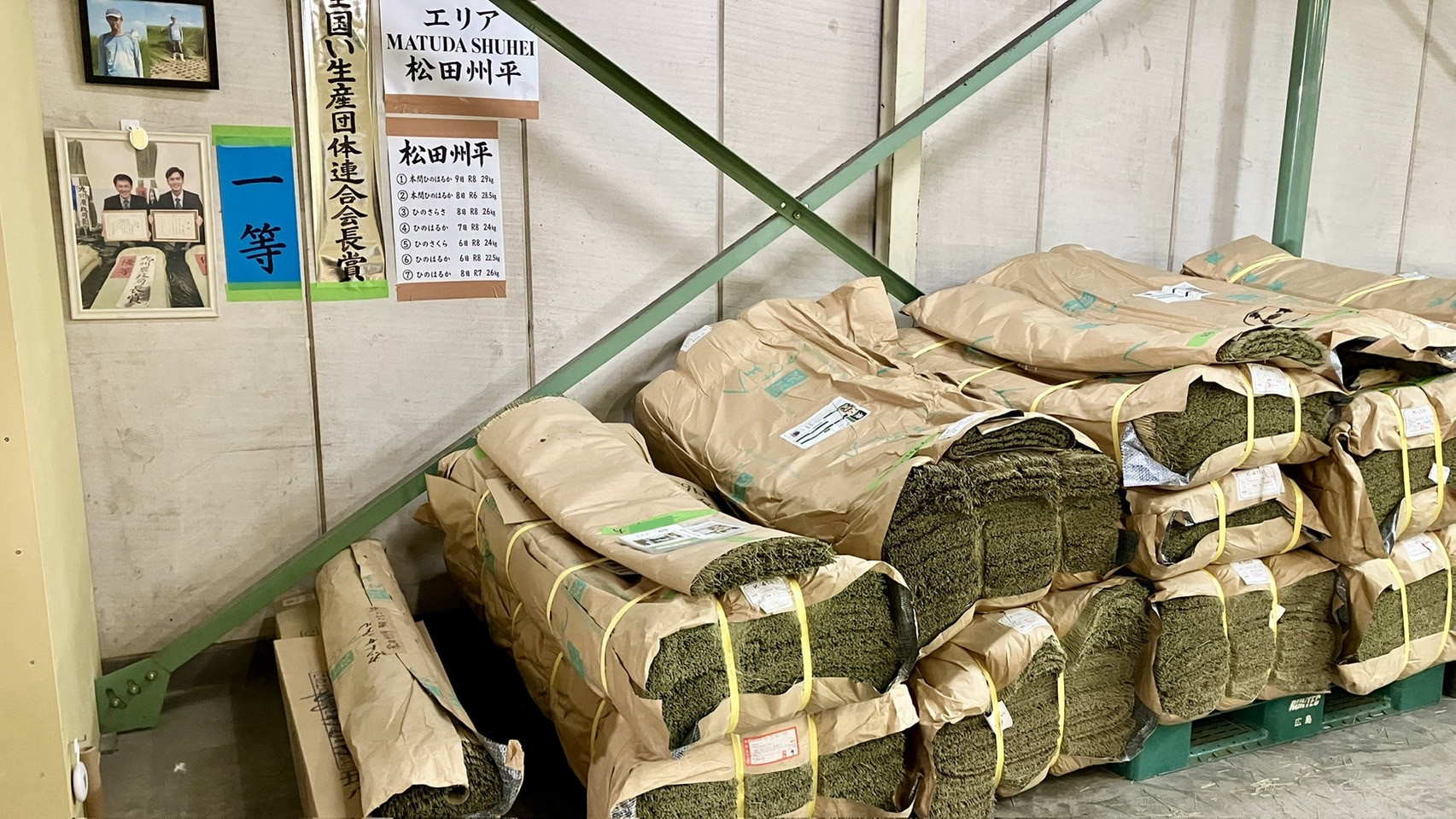 松田州平エリアの棚に誇らしげに掲げられた全国い生産団体連合会長賞の賞状と本間ひのはるかの実物写真｜佐藤畳工業