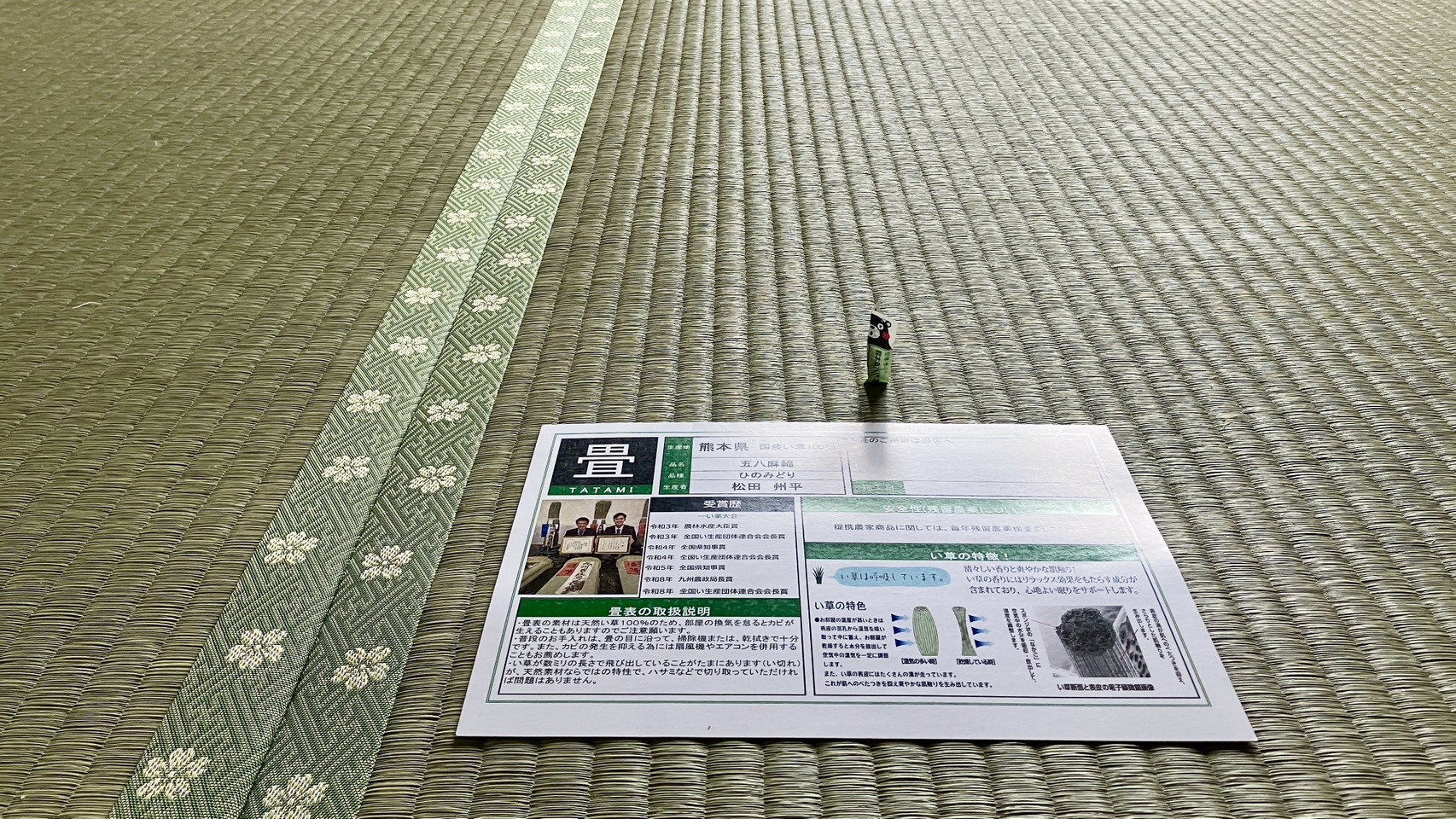 敷き込みが完了した新しい絢葉の畳の上に置かれた松田州平氏の顔写真付き国産畳表取扱説明書・品質証明書の写真｜佐藤畳工業