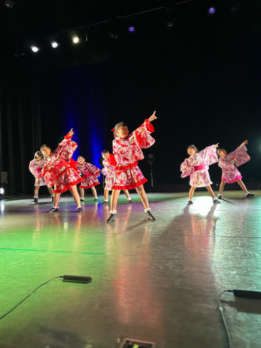 舞台で照明を浴びて着物ドレスで踊る女の子たち