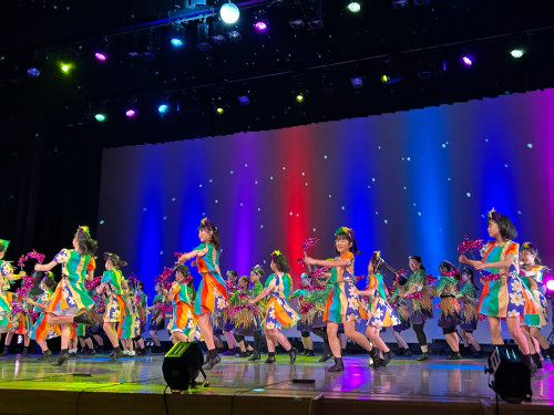 舞台で華やかに踊る子どもと大人たち
