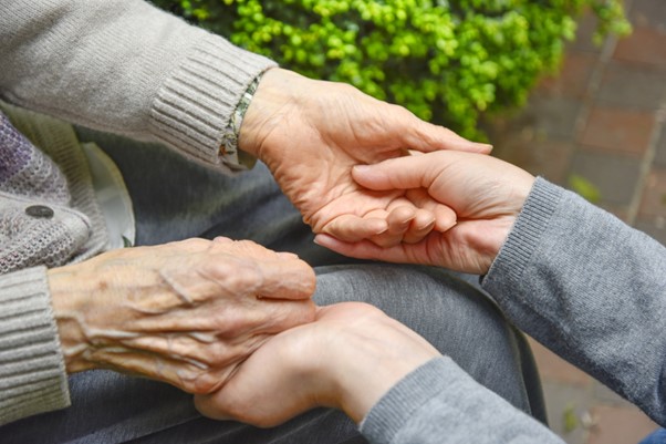 若い人の手が年配の人の手を支えている