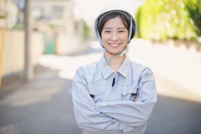 外で微笑む作業着の女性