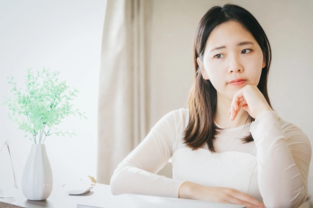 明るい部屋で考え込む女性