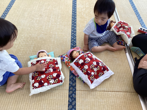 お人形を布団に寝かせる子どもたち