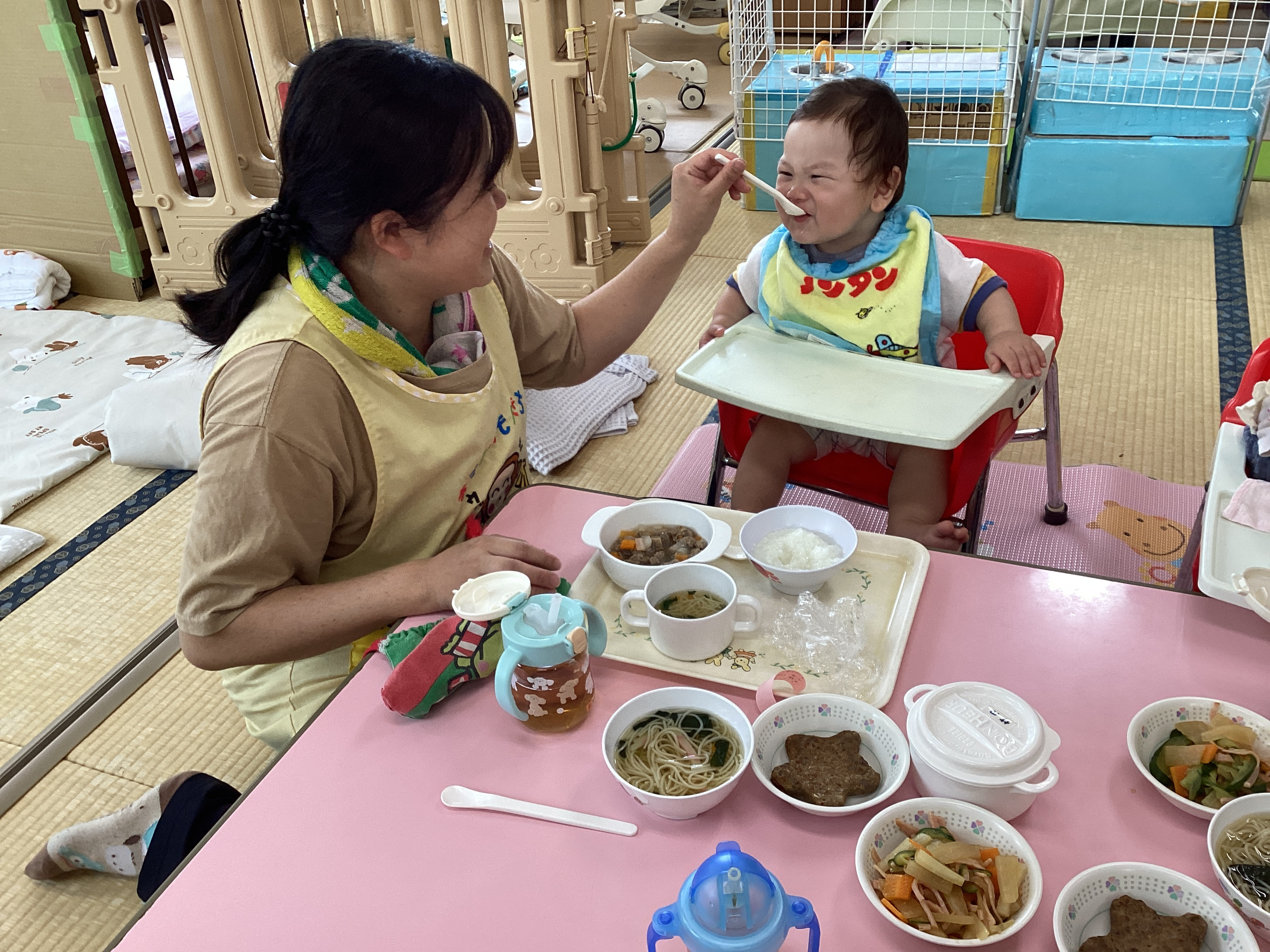 保育士と一緒に給食を食べる子どもたち