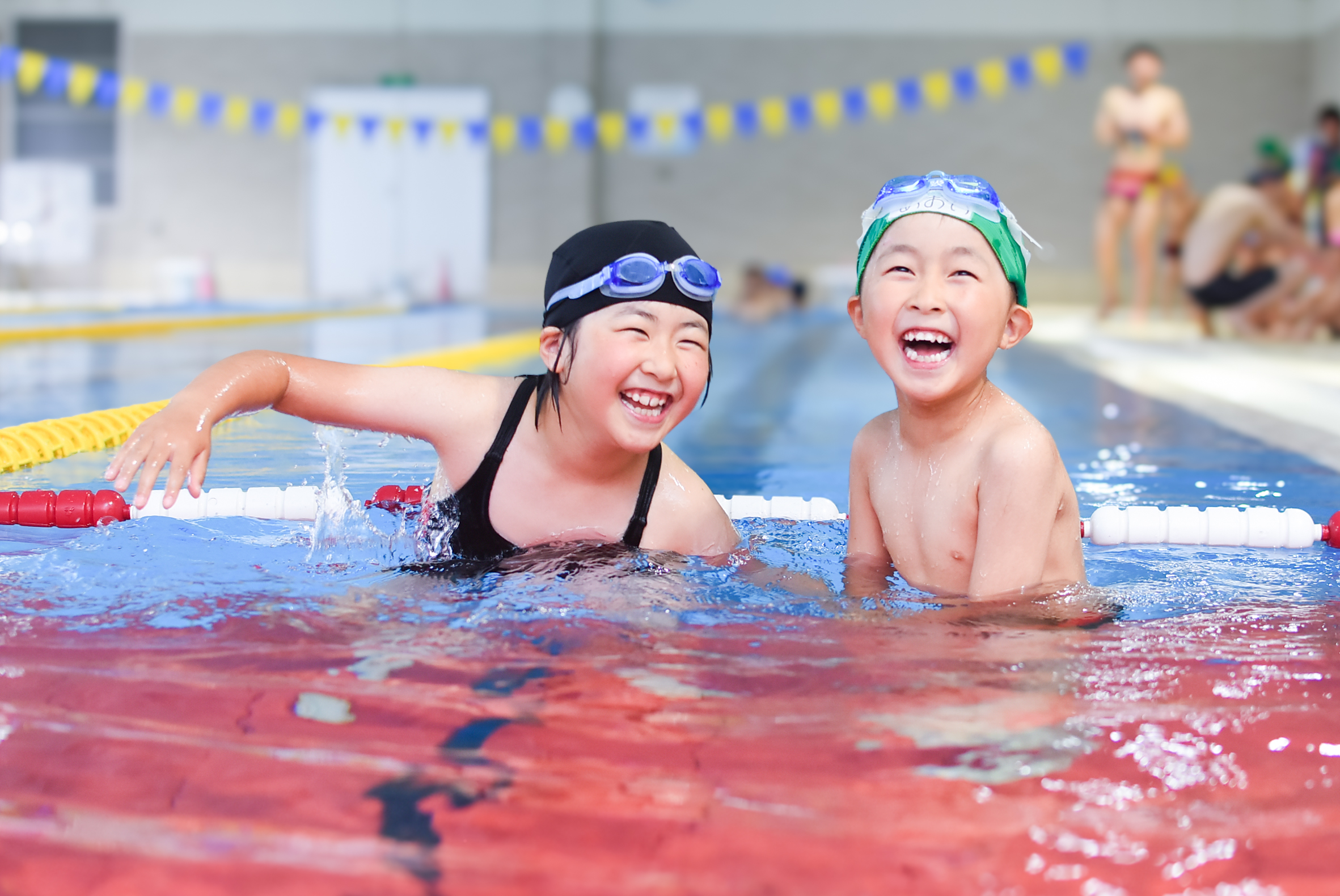 プールで笑顔を見せるスイミングスクールの子どもたち
