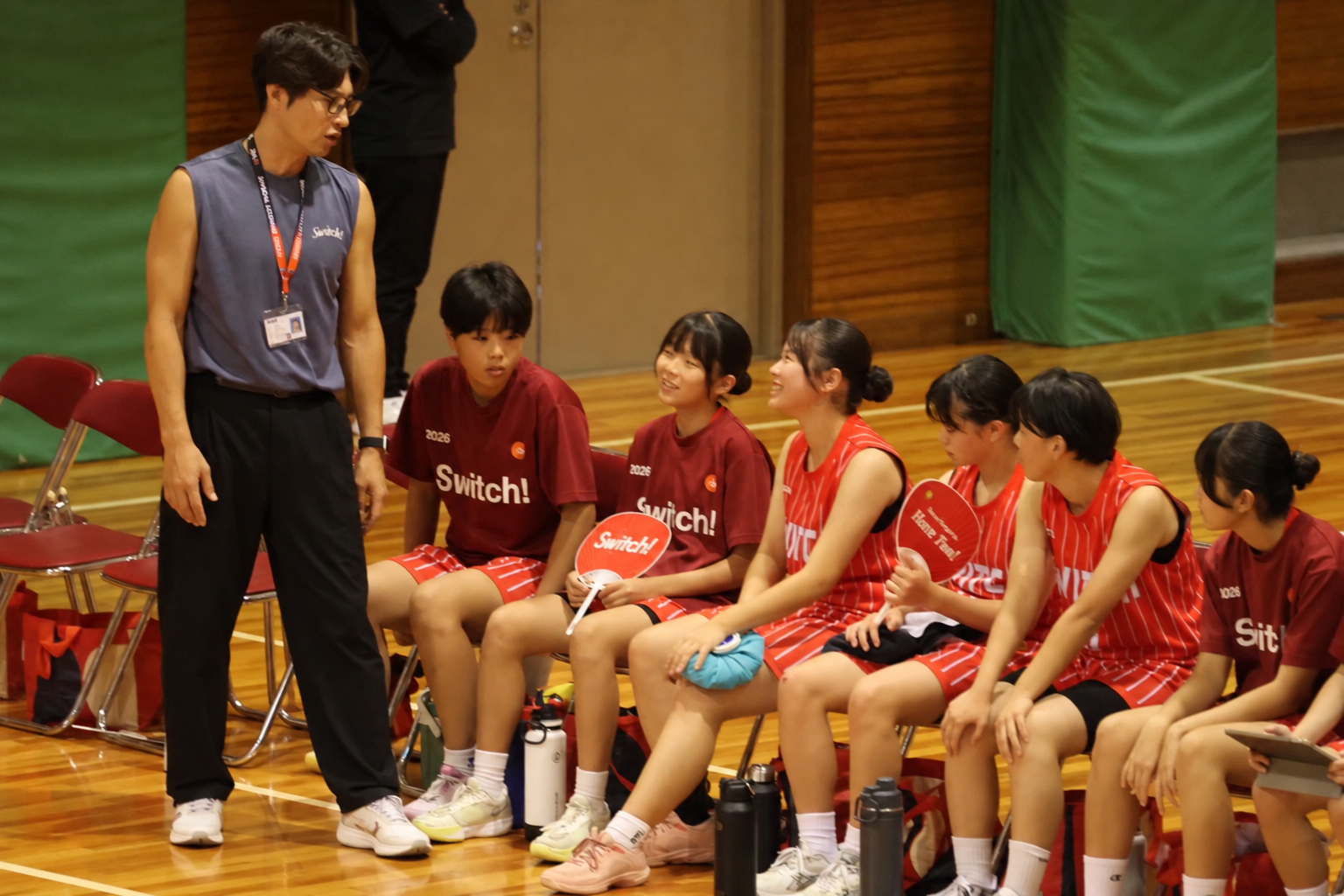 U15女子がベンチで仲間やたけおコーチと笑顔で話す場面