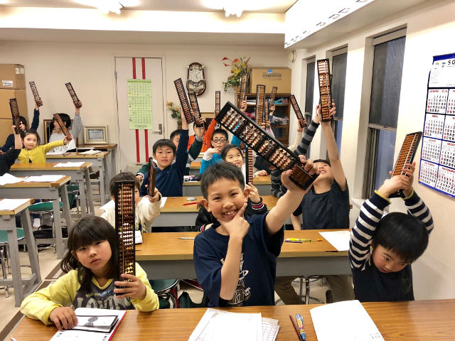 そろばんを持ちあげている子供