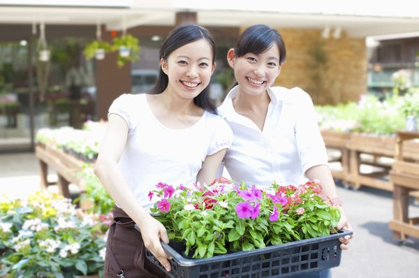 花を持って微笑む2人の若い花屋の女性店員の画像。「みんなで使える」ので喜んでいるイメージ
