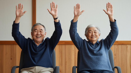75歳男女椅子に座って両手あげてバンザイ笑顔・長袖・日本人体操している.jpg